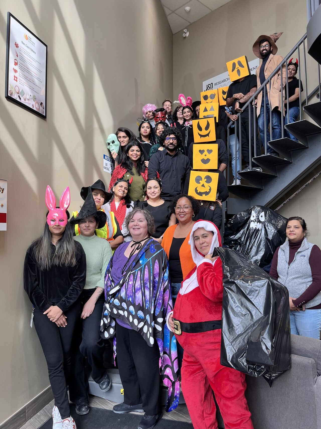 Group of people in costumes posing on stairs.