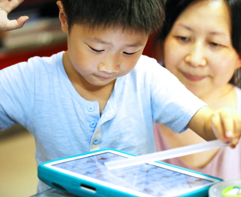 Child communicating with his mother through his Tobii Dynavox Indi touch device 