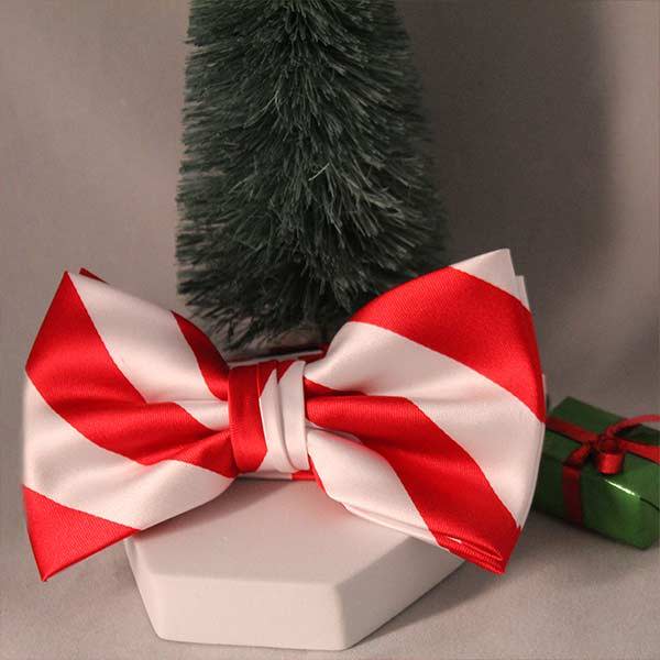 A red and white striped bow tie with a Christmas tree and present prop