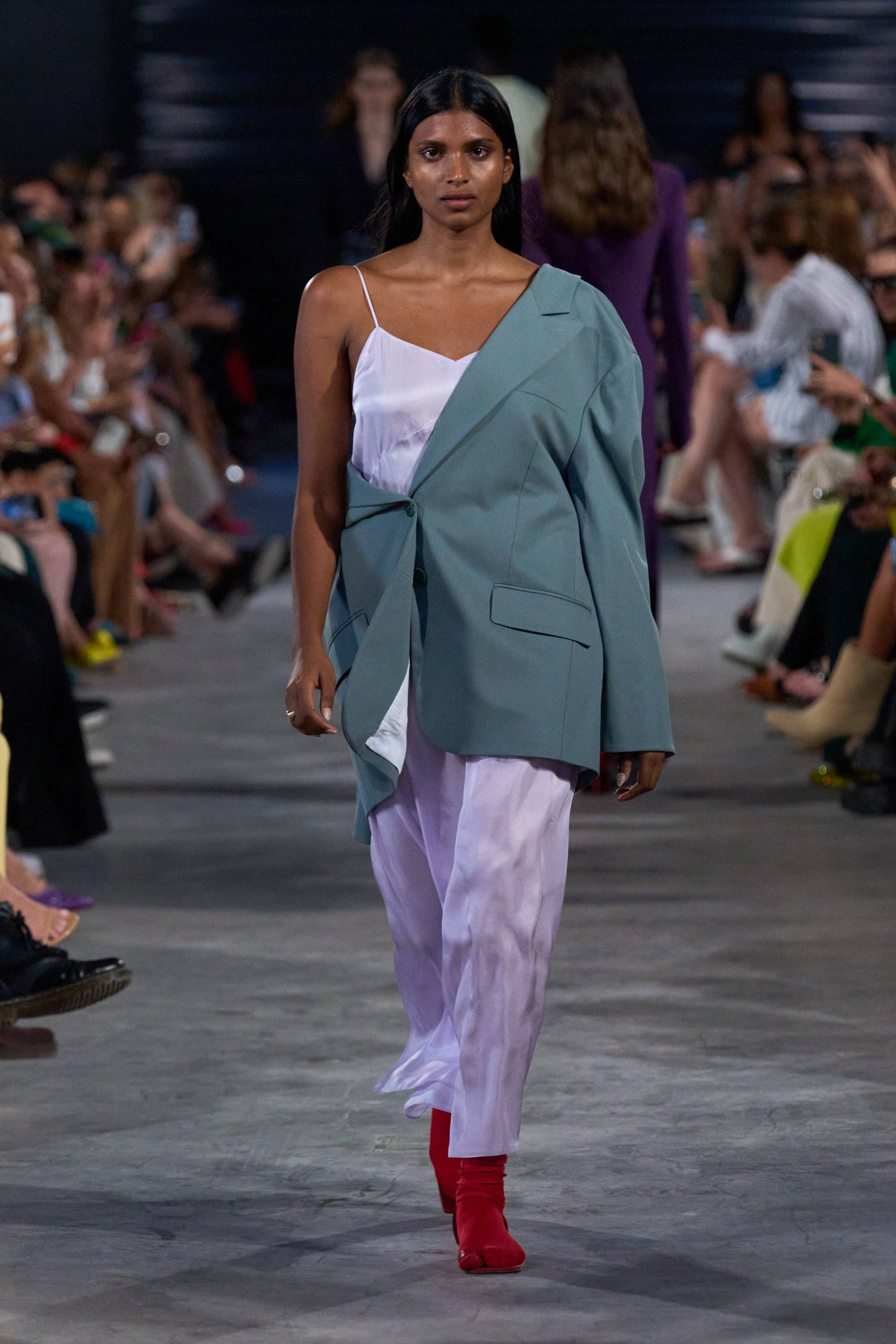 Model on a runway wearing blazer and slip dress
