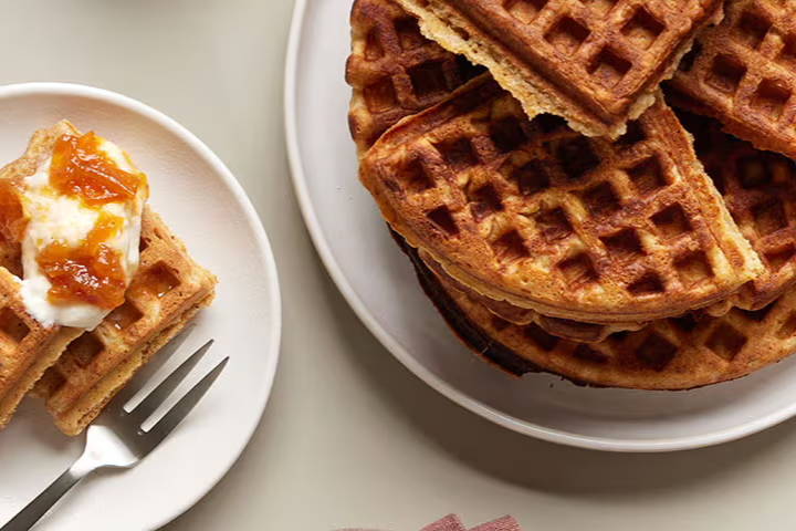 A plate of waffles with a serving on the side.