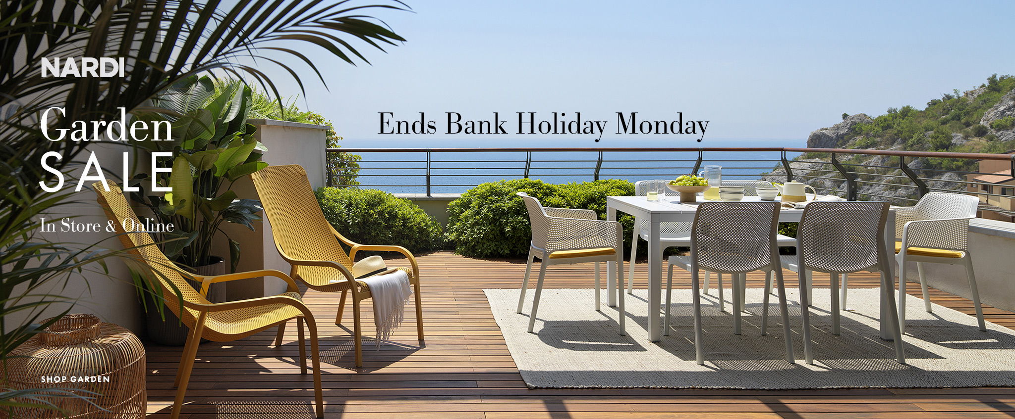Outdoor dining area with furniture overlooking a scenic view. Garden sale promotion.