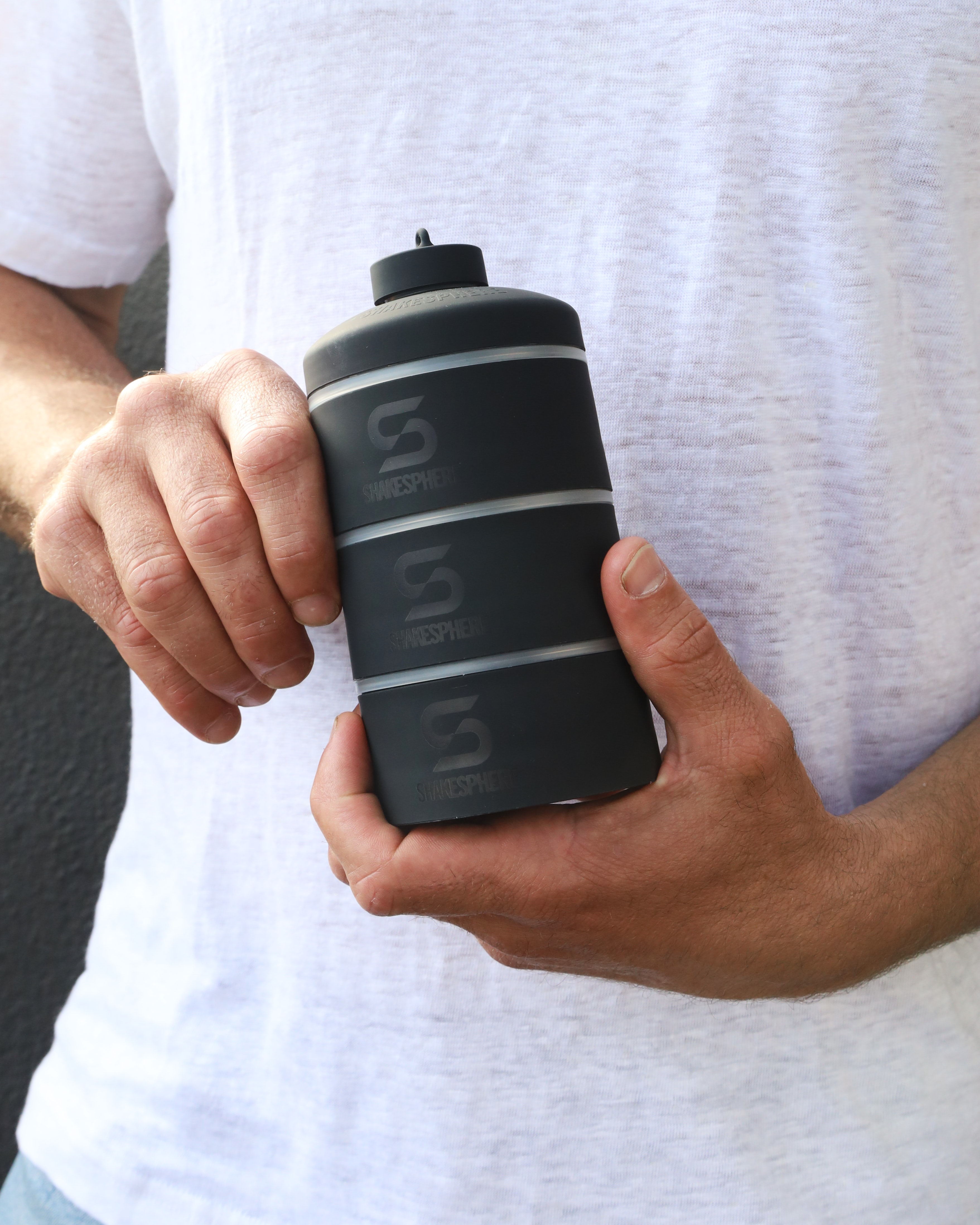 Person holding a black cylindrical container with three horizontal stripes.
