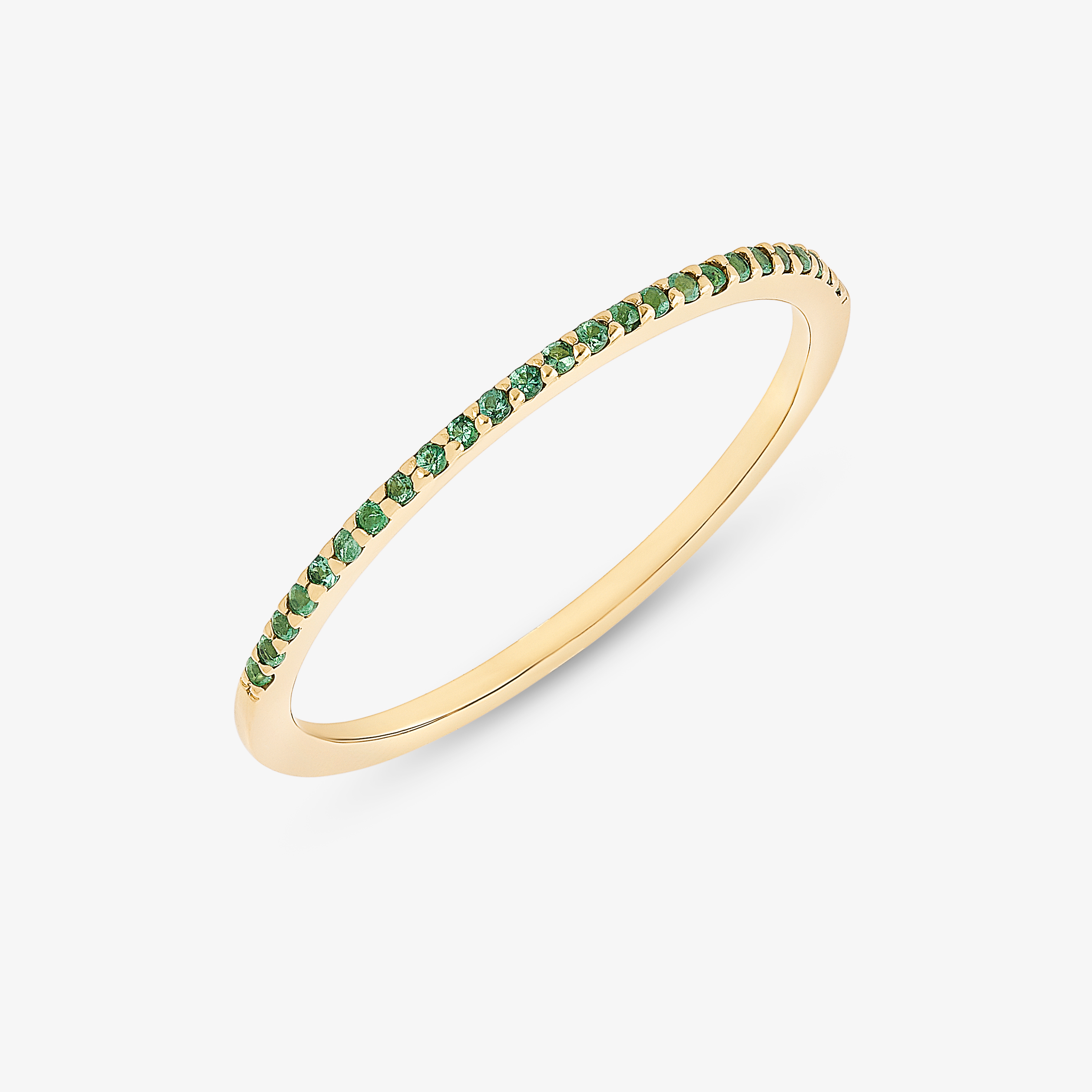 Gold ring with green gemstones set along the band.