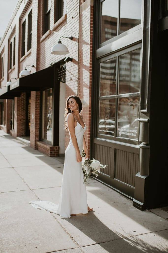 Bride wearing the Grace Loves lace Summer Silk wedding dress holding white bouquet