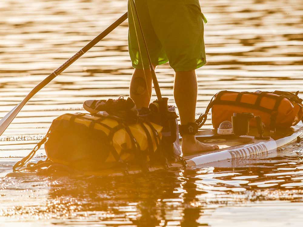 Paddling the Endurance stand up paddle board at sunset with gear strapped to the paddleboard