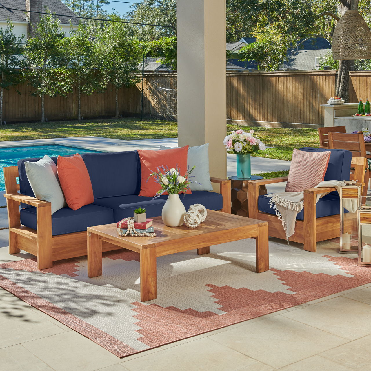 Outdoor seating area with wooden furniture, colorful cushions, and a swimming pool nearby.