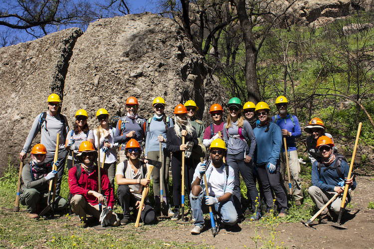 Group of volunteers with hard hats and tools ready to restore trails