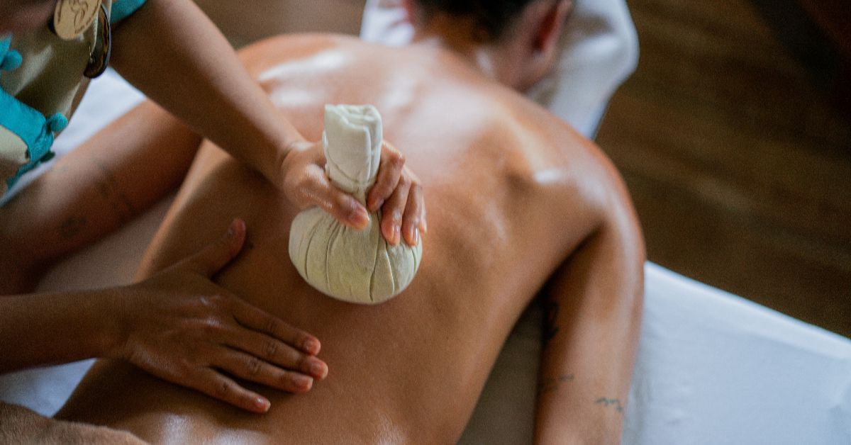 Person receiving a massage with a Thai compress on their back.
