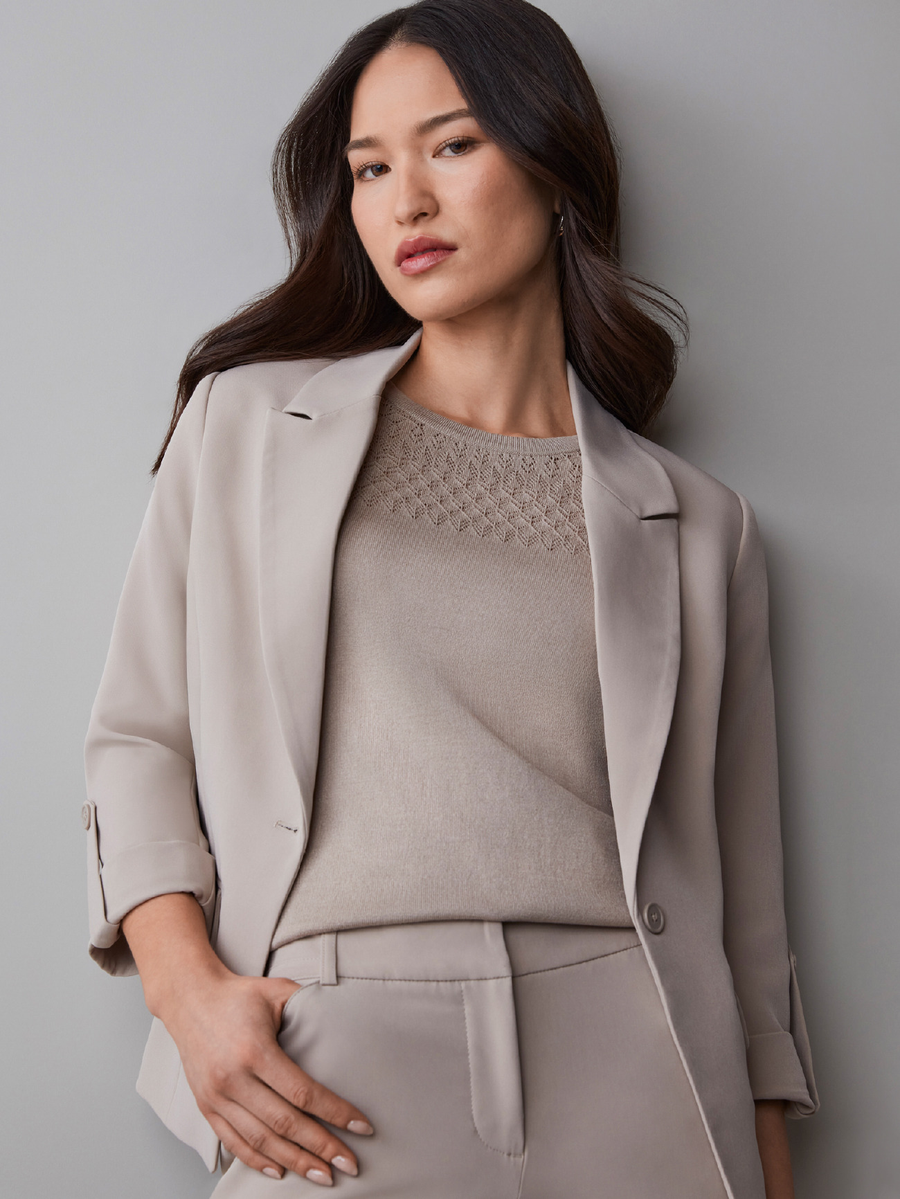 Woman in a beige suit against a neutral background, looking confidently at the camera.