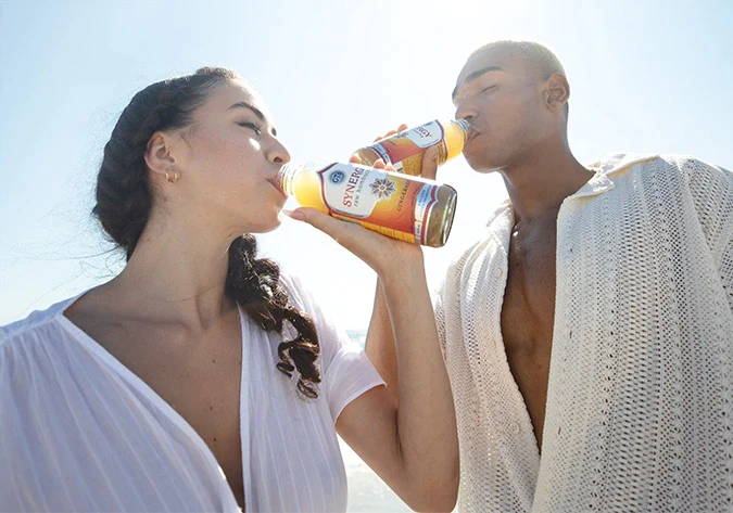 Man and woman drinking SYNERGY on a beach