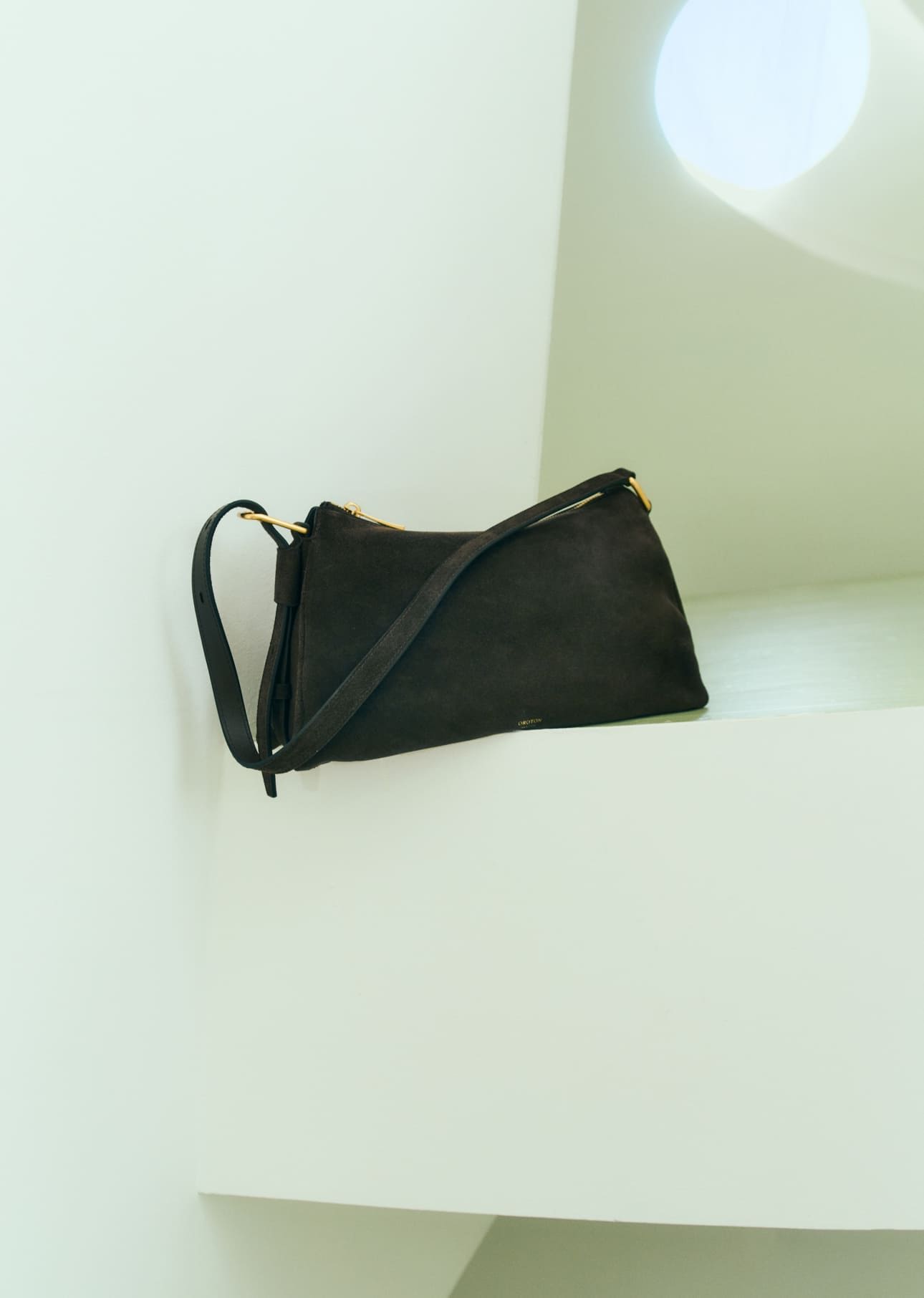 Black handbag resting on a white geometric surface.