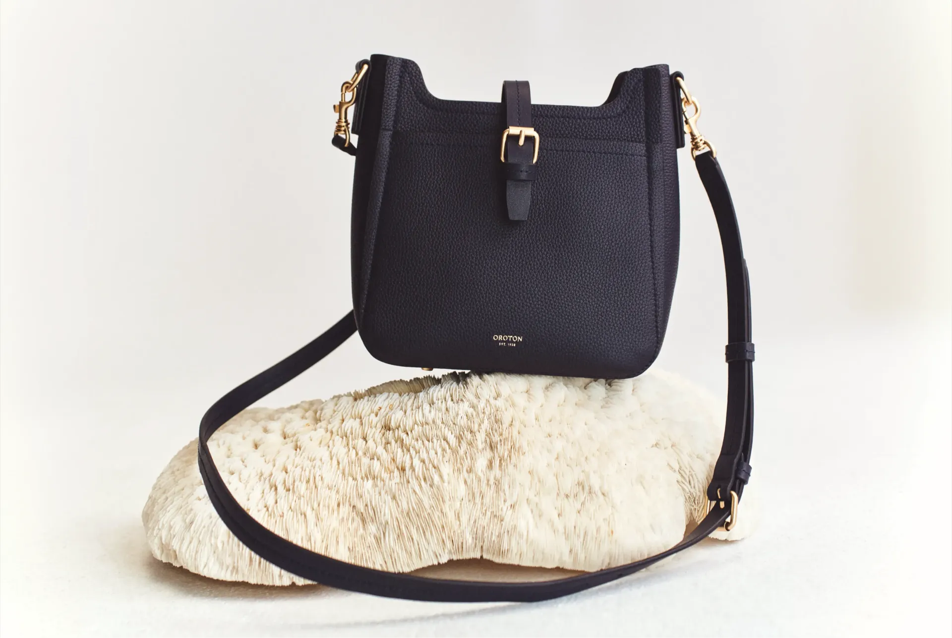 Black handbag with gold accents on a light stone surface.