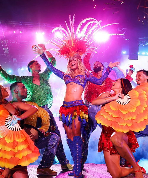 Colorful dancers performing on stage with vibrant lighting and costumes.