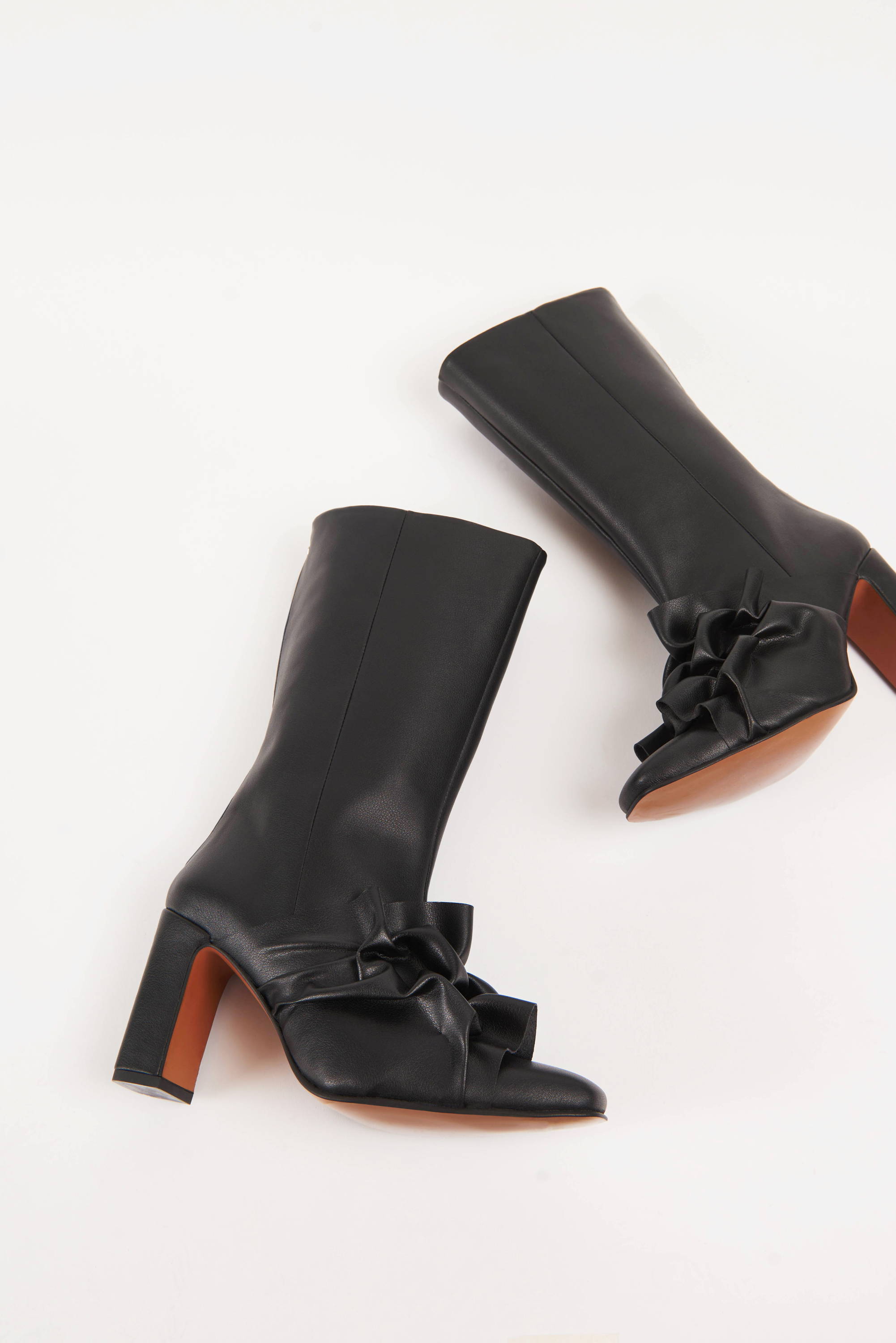 A pair of Vandrelaar black high-heel ankle boots made from vegan leather with brown sole featuring canadian smocking detailing