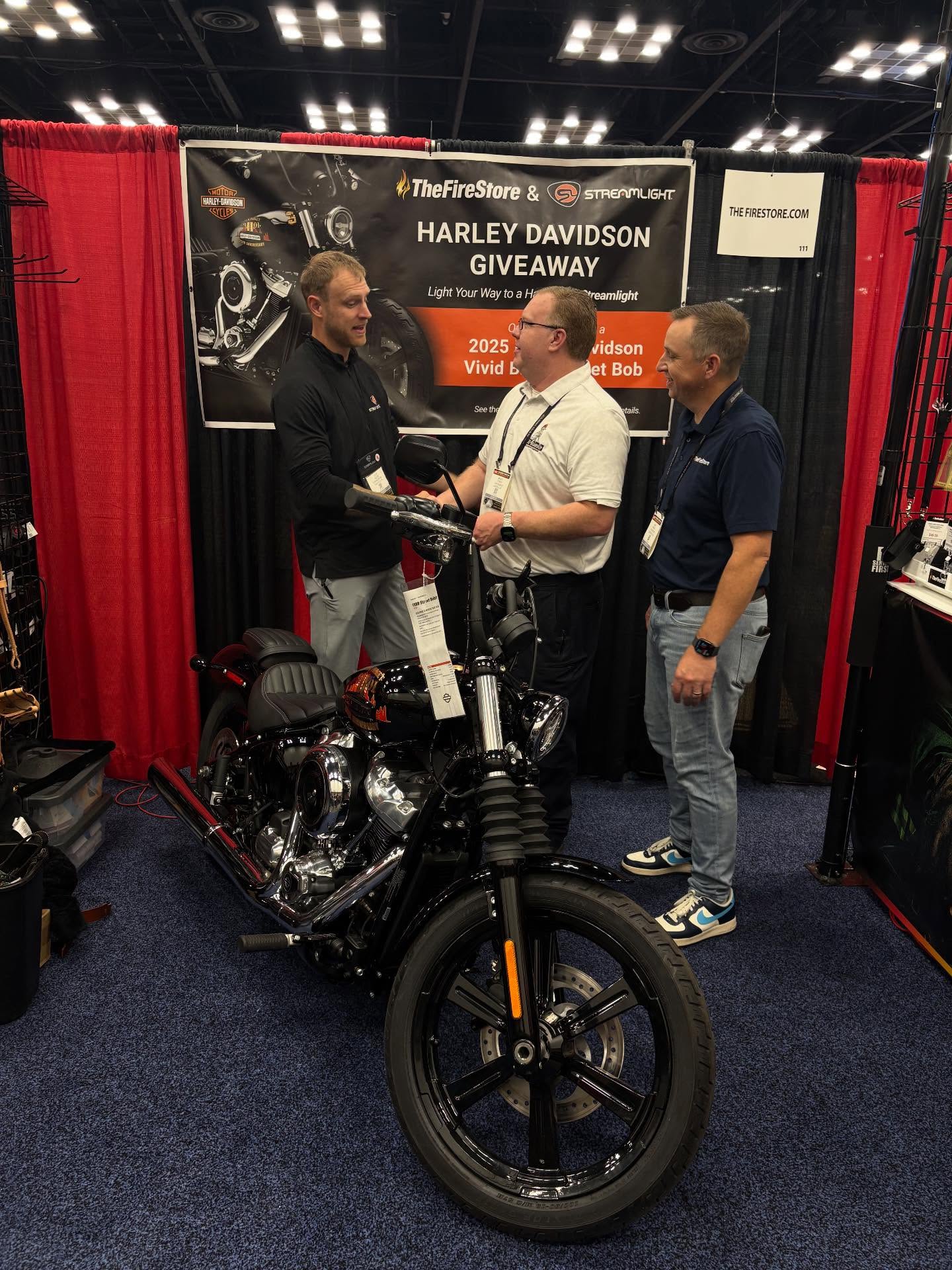 Two people discussing a motorcycle at a trade show booth.