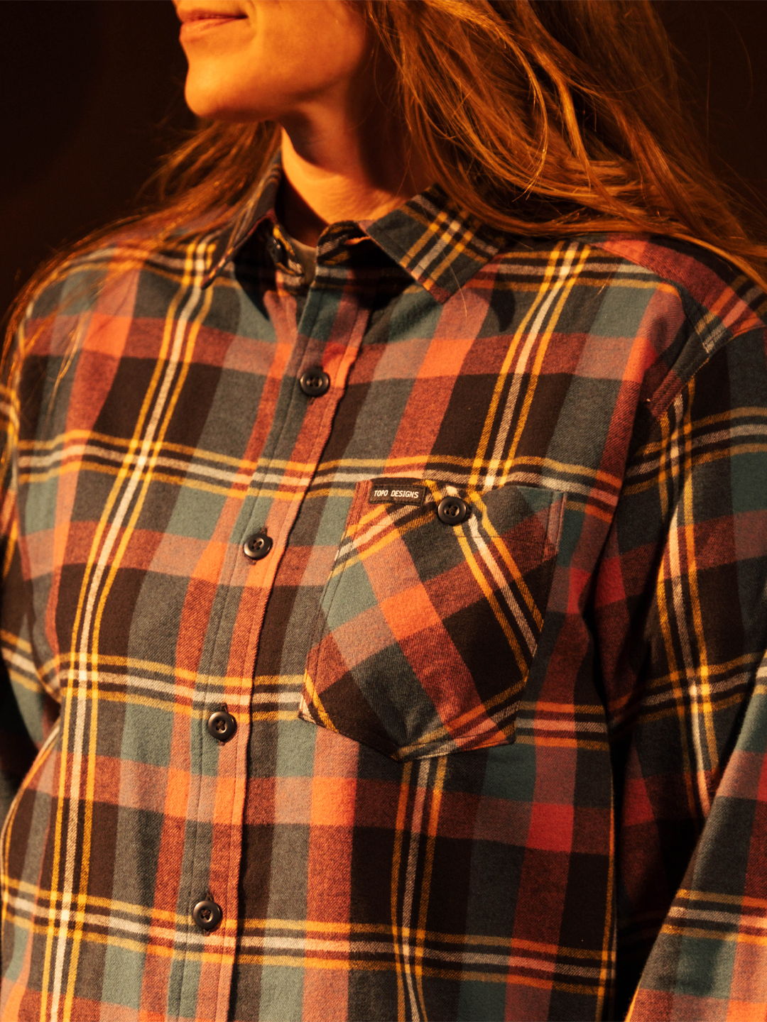 Person wearing a colorful plaid shirt with a pocket.