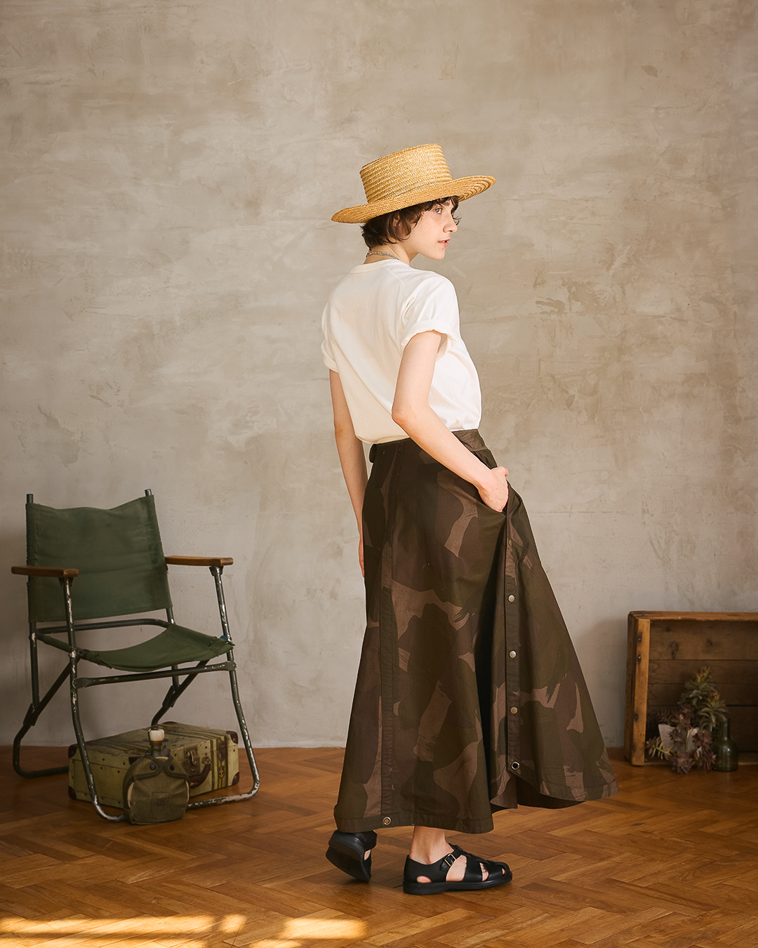 Woman in a stylish outfit with a hat, standing in a room.