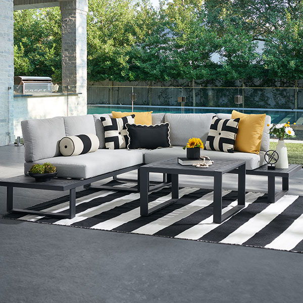Outdoor seating area with cushions, table, and striped rug.