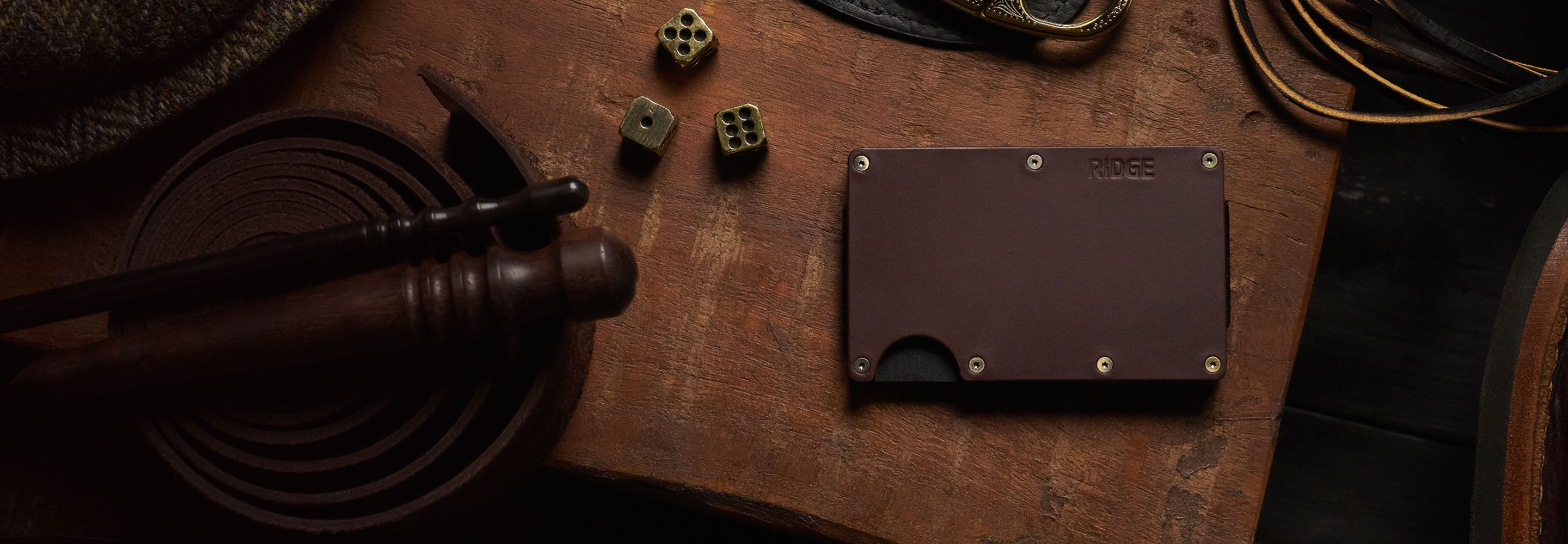 A brown wallet on a wooden surface with small objects nearby.
