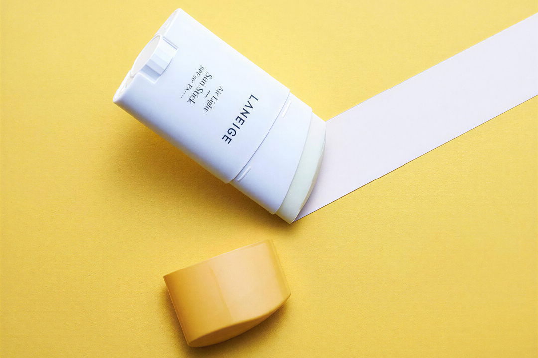 A white tube of cream on a yellow background with a yellow cap.