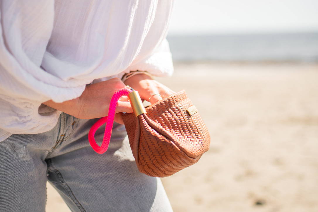 woman reaching into brown basketweave clam shell bag