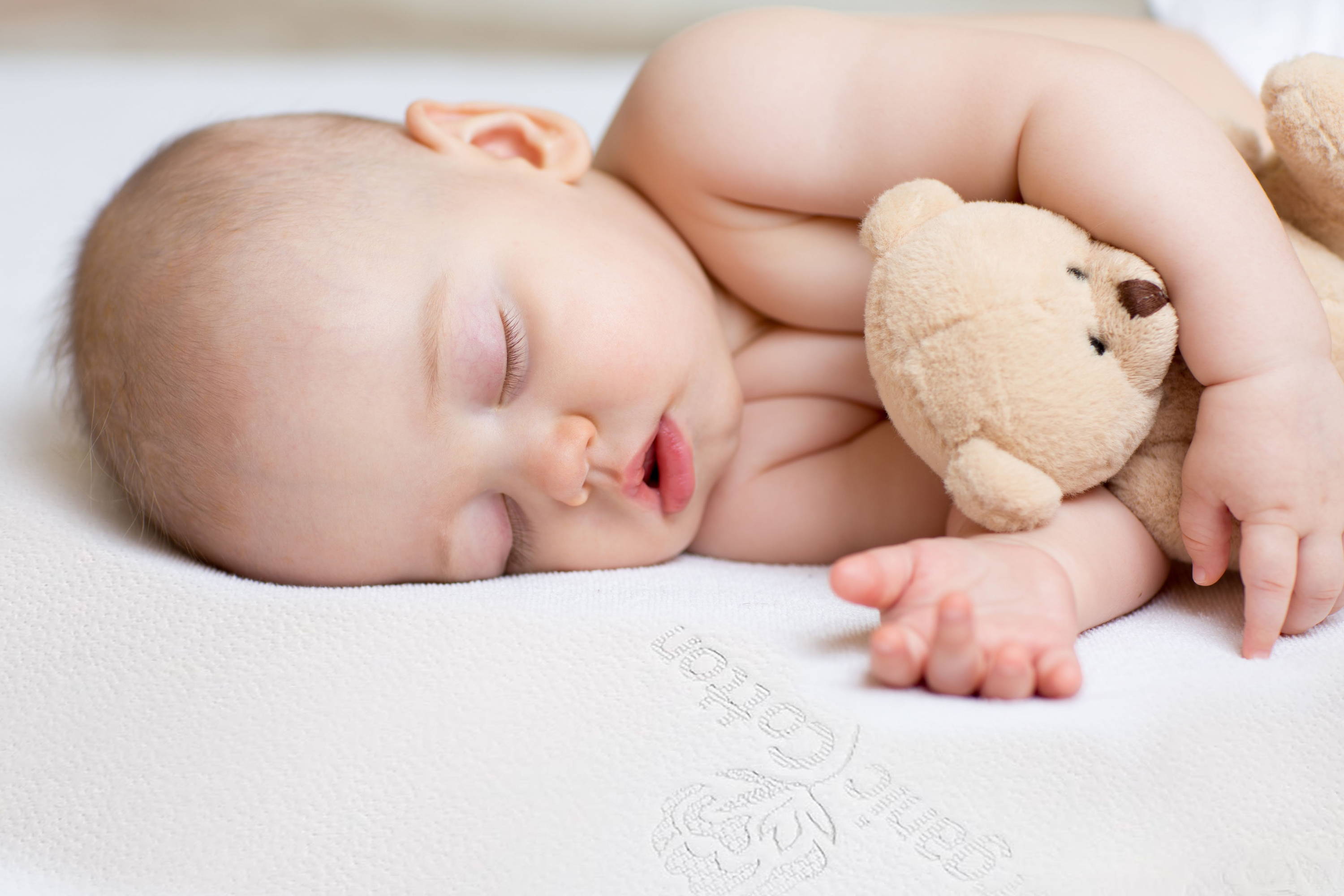 Sleeping baby on a healthy organic crib mattress that is firm to help prevent SIDS.