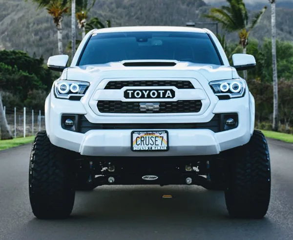 Head-on lifted white Toyota Tacoma black mesh grille halo rings CRUSE7 off-road tires palms Christian's Conductor's Special 232 gallery photo 3