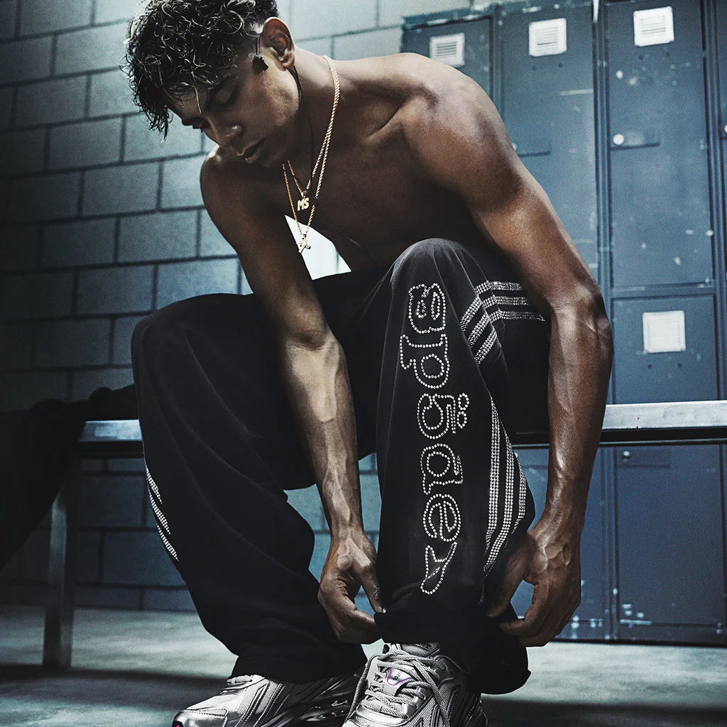 Athletic individual tying shoes, wearing sporty attire in a locker room.