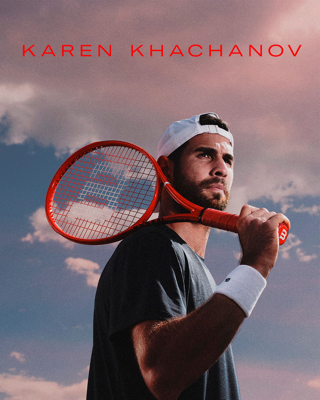 Tennis player holding a racket against a colorful sky background.