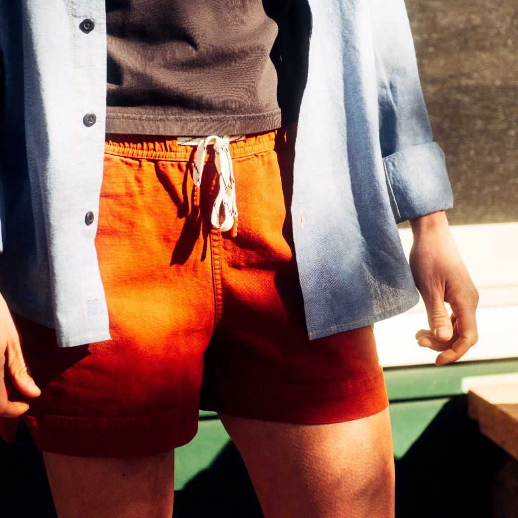 Person wearing orange shorts and a light blue shirt, standing outdoors.
