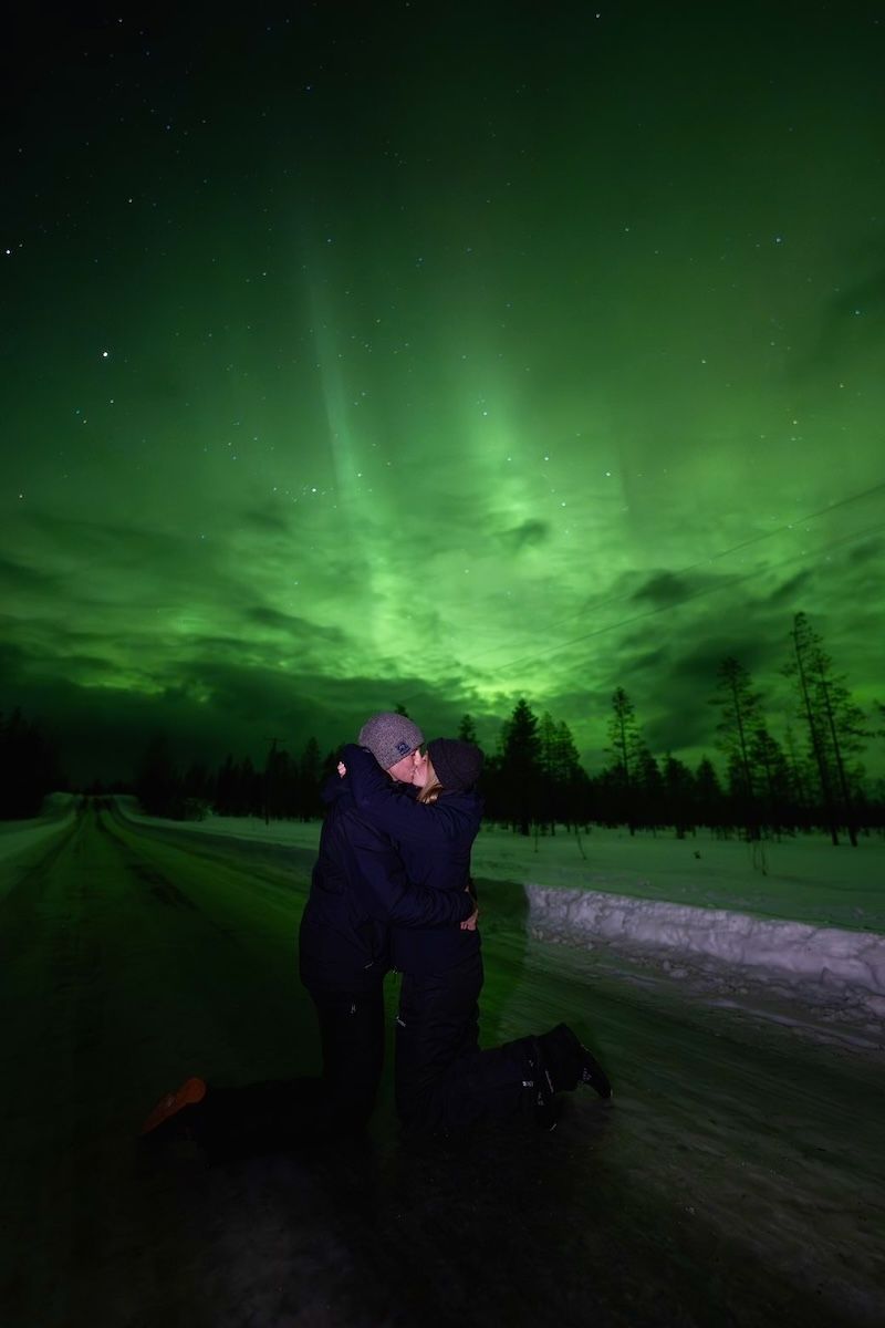 couple getting engaged with northern lights in background