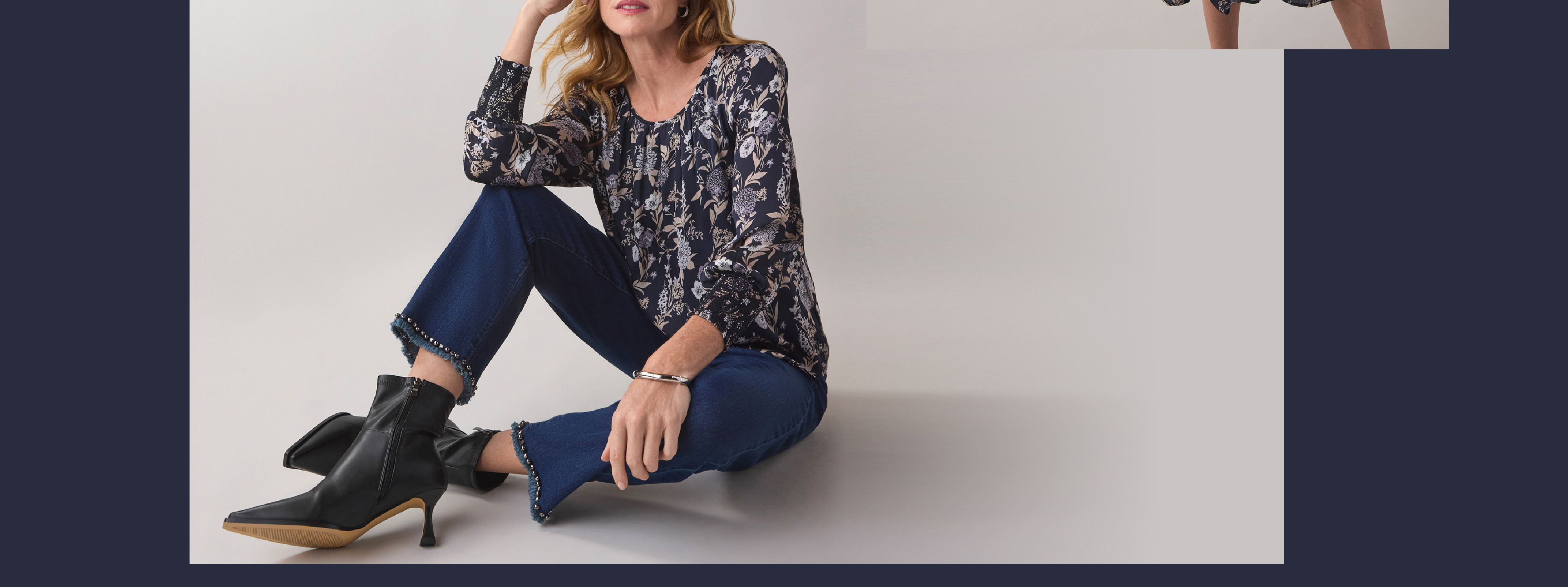 Woman sitting in stylish outfit with boots and casual clothing.