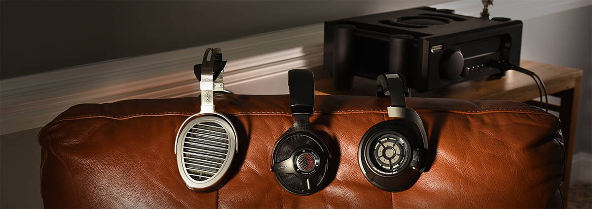 Three headphones lined up against back of chair