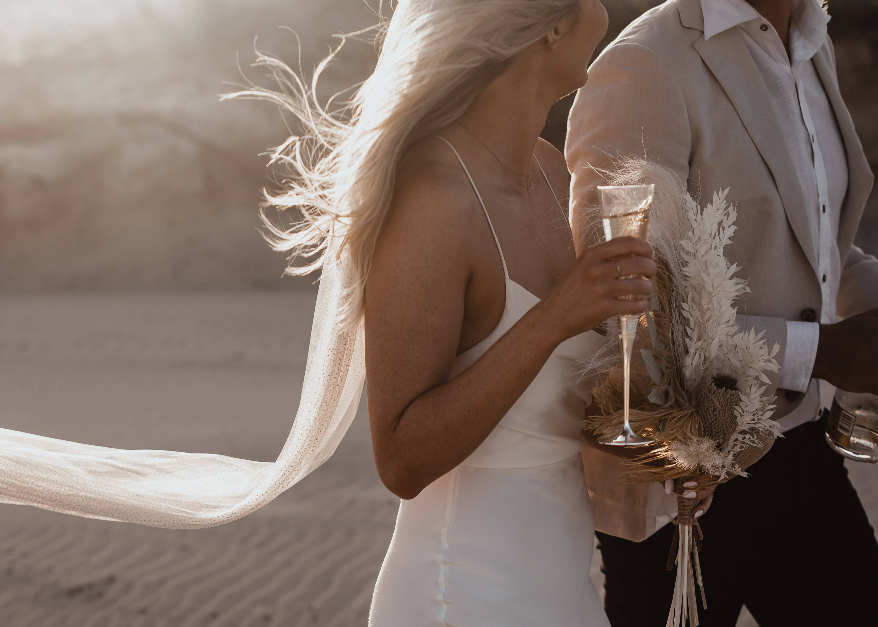 Bride in thin strap dress holding champagne class