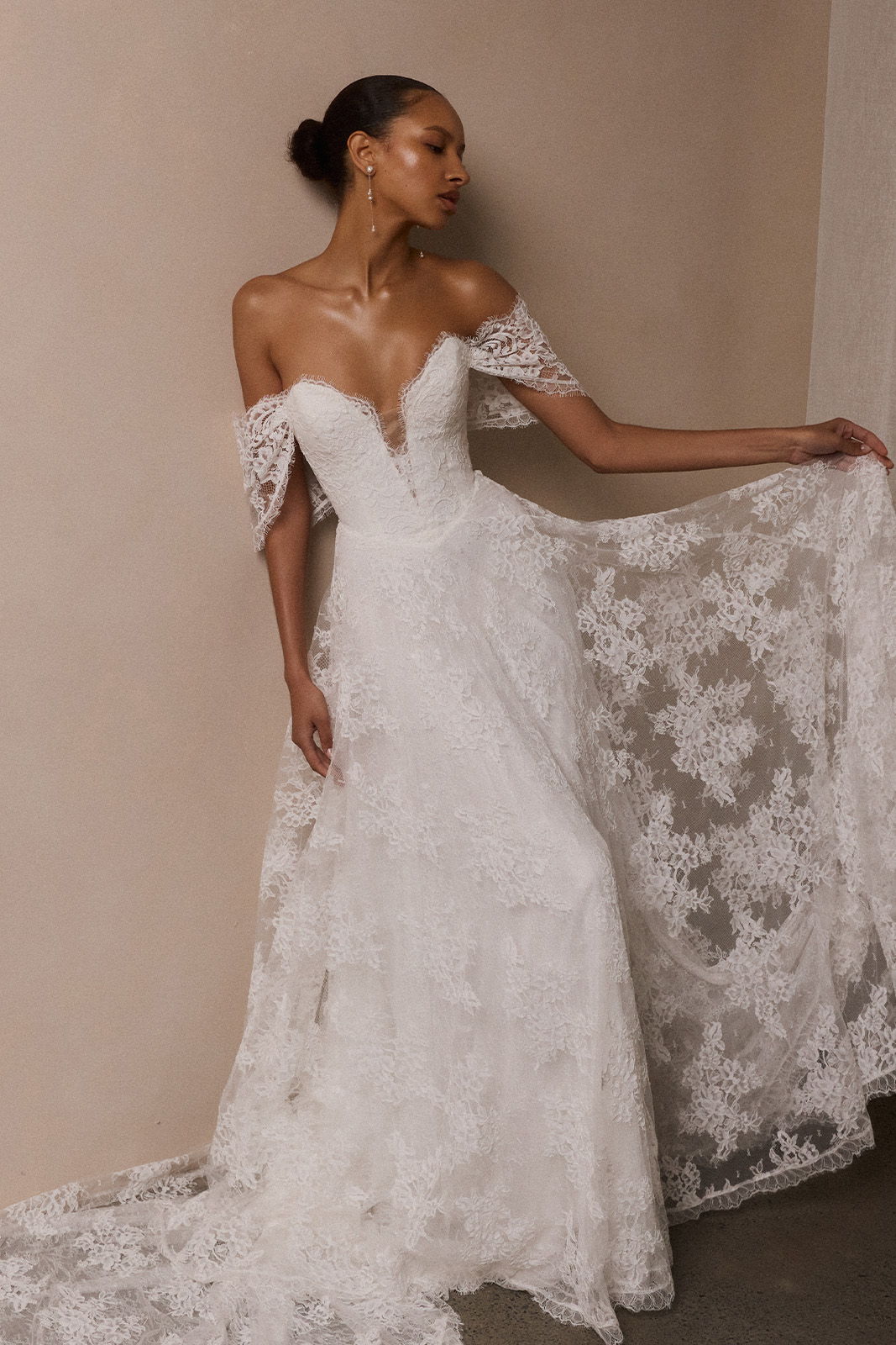 A woman in a stunning lace wedding dress with off-shoulder sleeves.