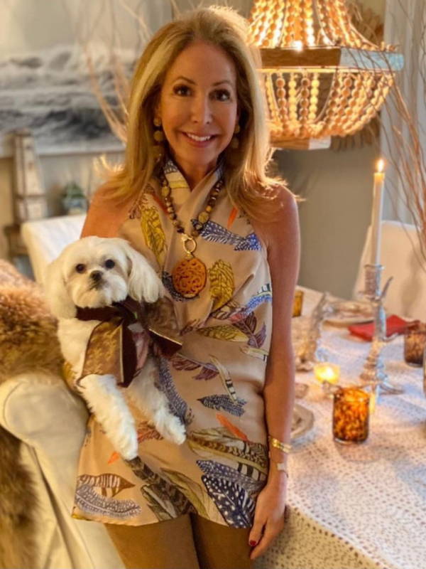 Meg McCartney wearing feather printed silk halter top with her dog and matching tablescape