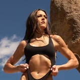 Female in a black swimsuit posing outdoors near a large rock.