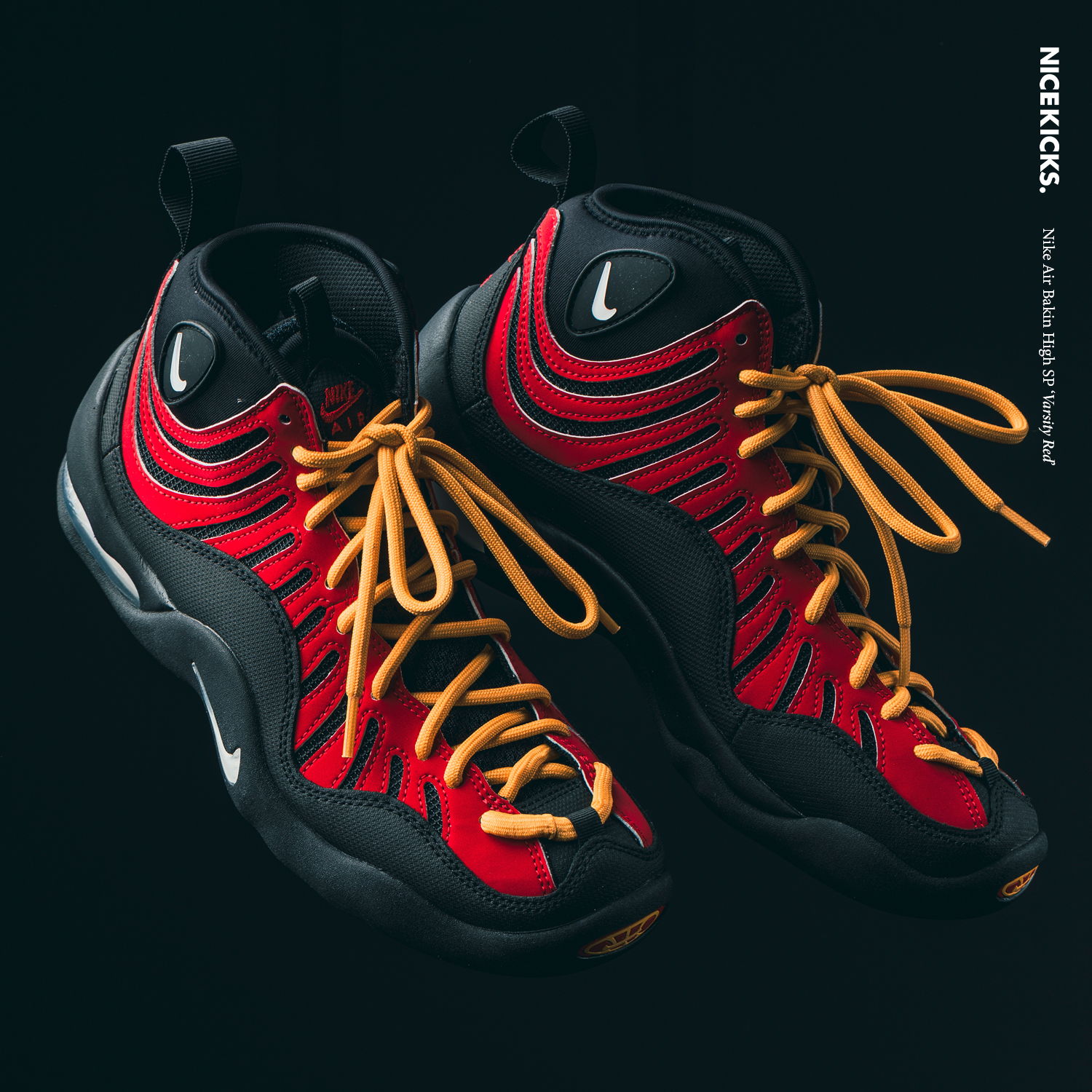 Red and black Nike sneakers with orange laces on a dark background.