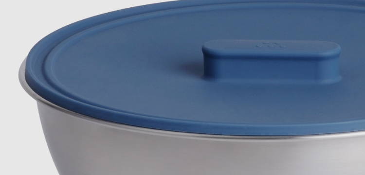 A Blue Misen Universal Lid with raised handle forming an airtight seal on a stainless steel saucier.