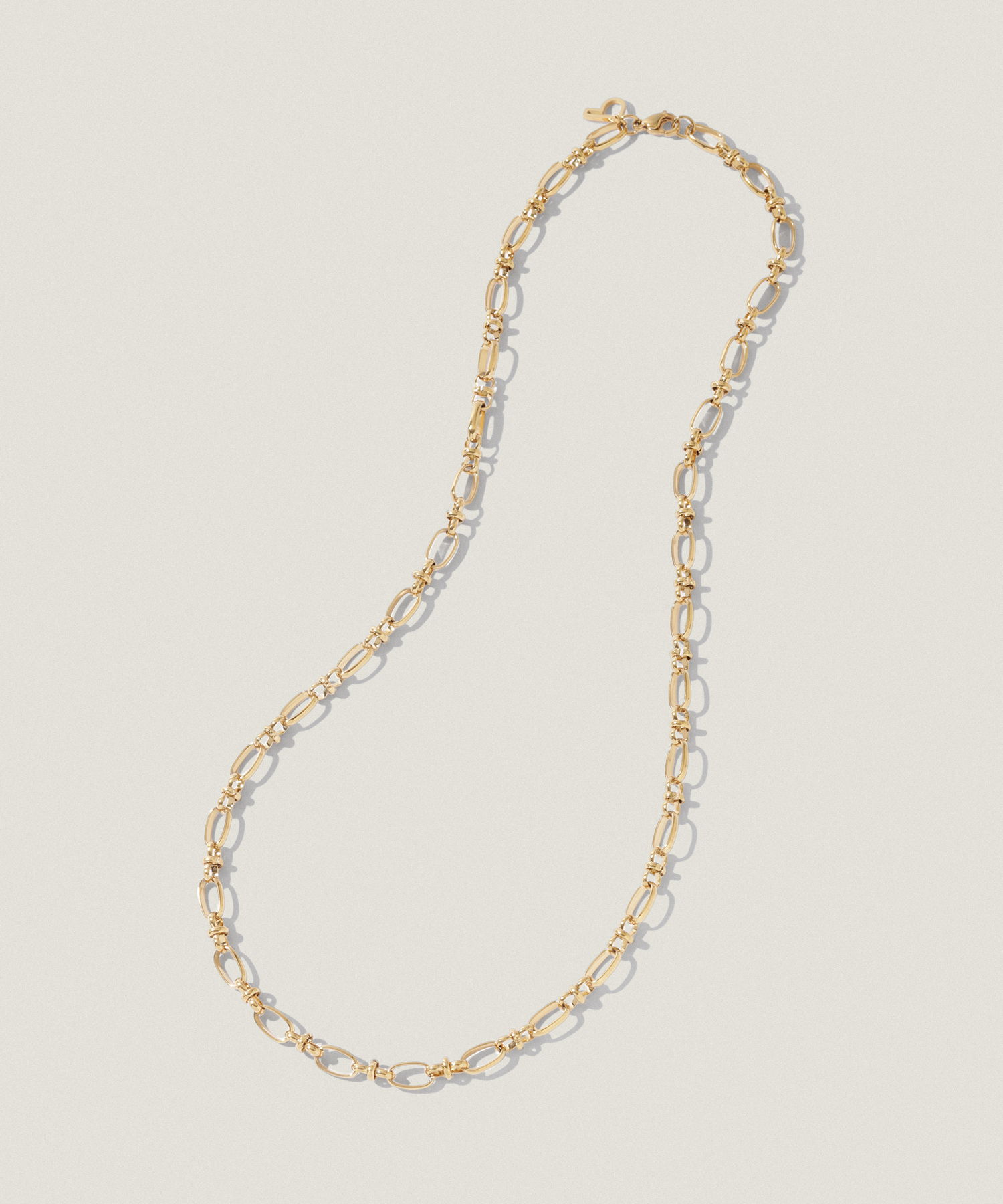 Gold chain necklace with circular links on a neutral background.
