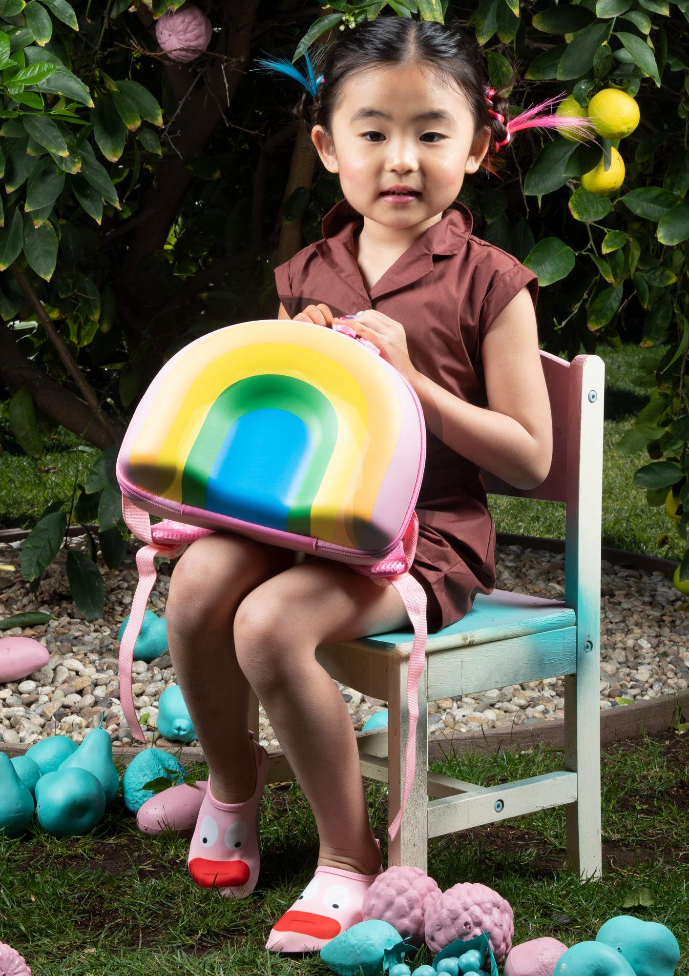 Young girl sitting on a chair with a rainbow backpack