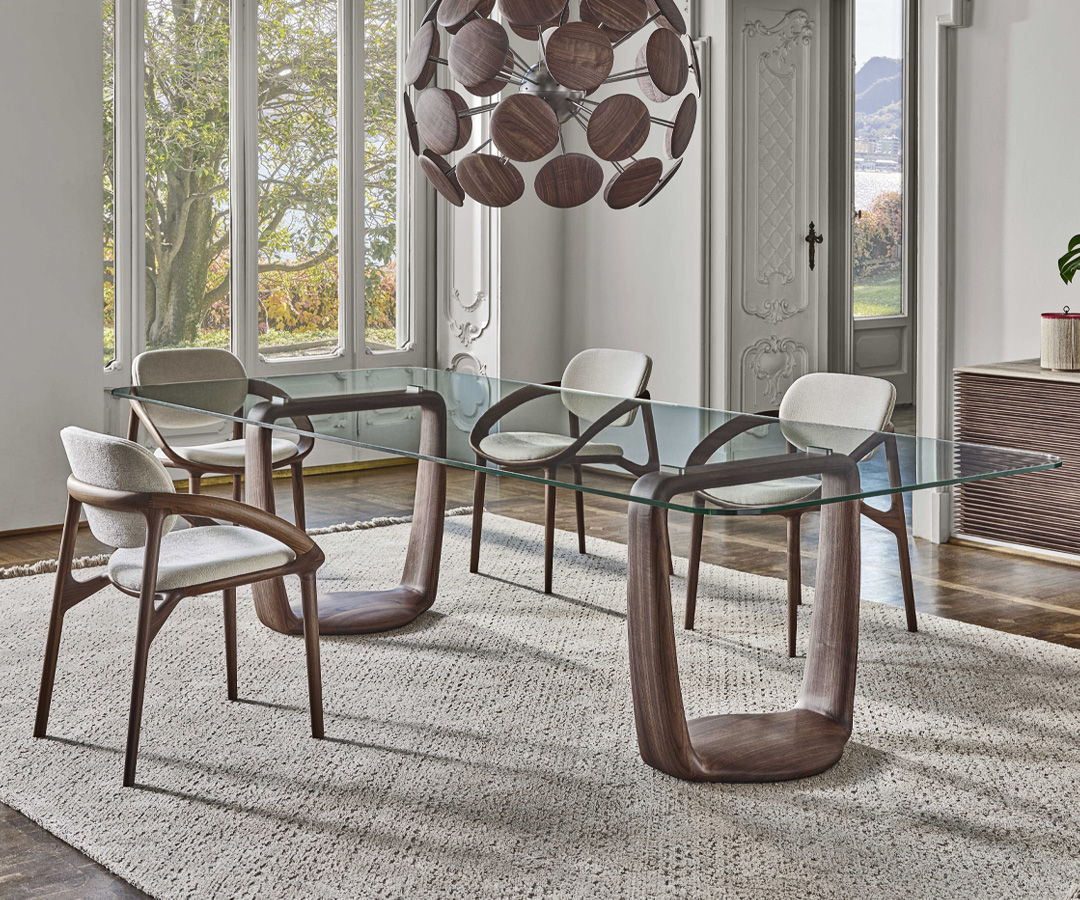 Modern dining room with a Porada glass table, stylish chairs, and a decorative light fixture.