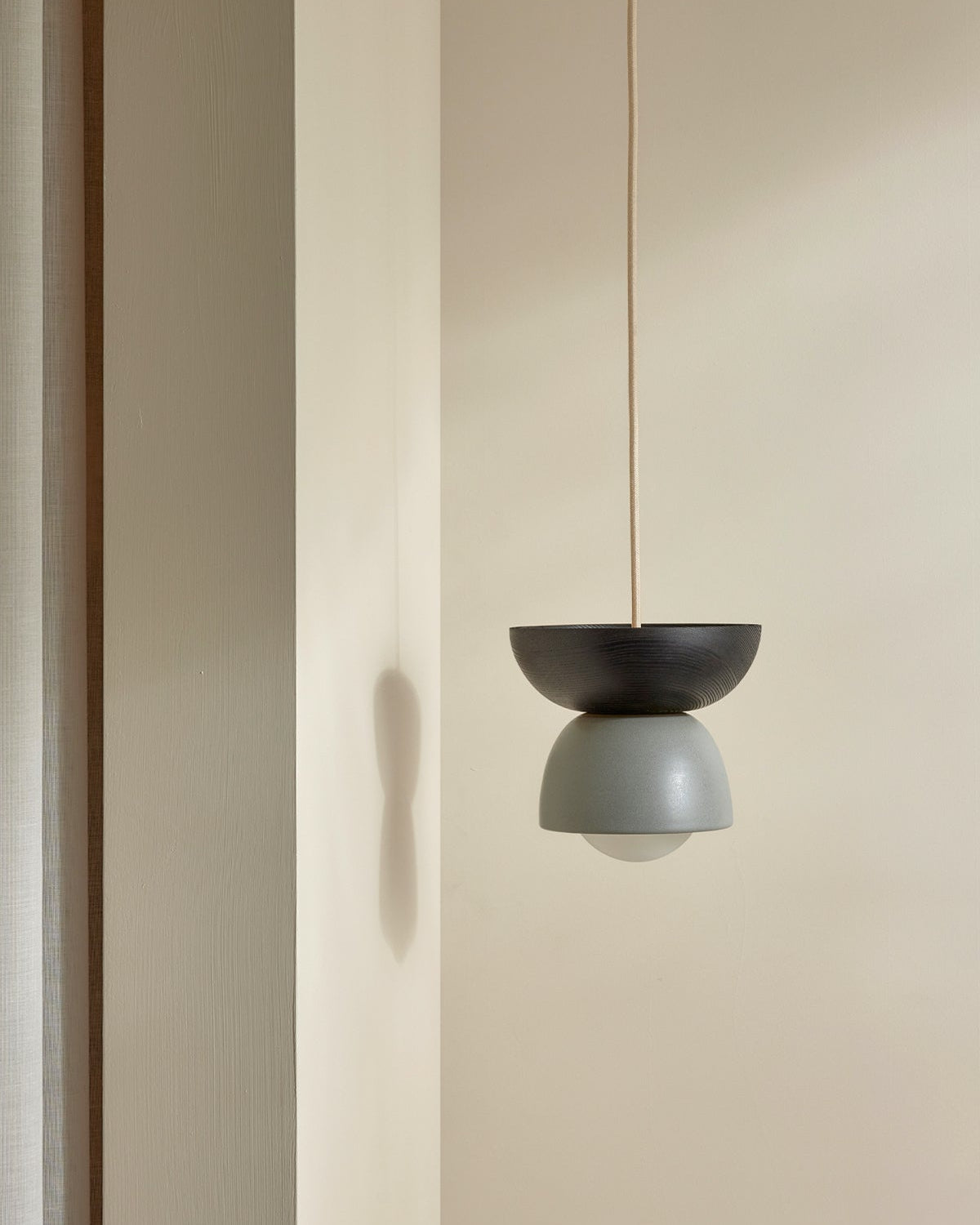 Minimalist pendant light hanging against a neutral wall.