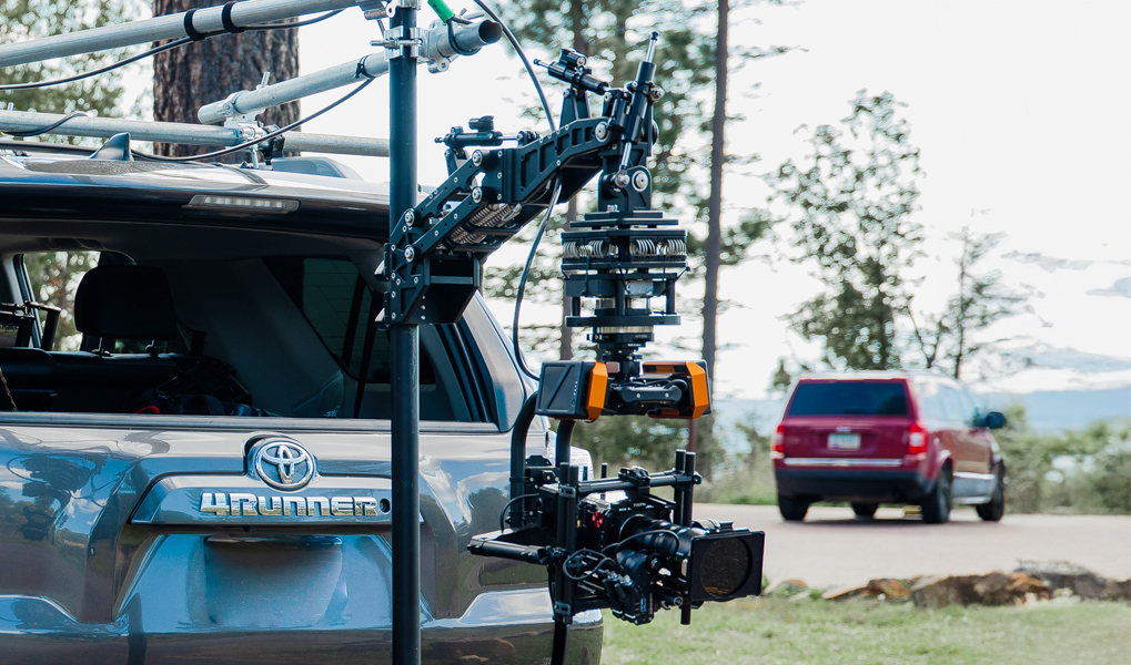 Camera mounted on a vehicle with a scenic background and another vehicle nearby.