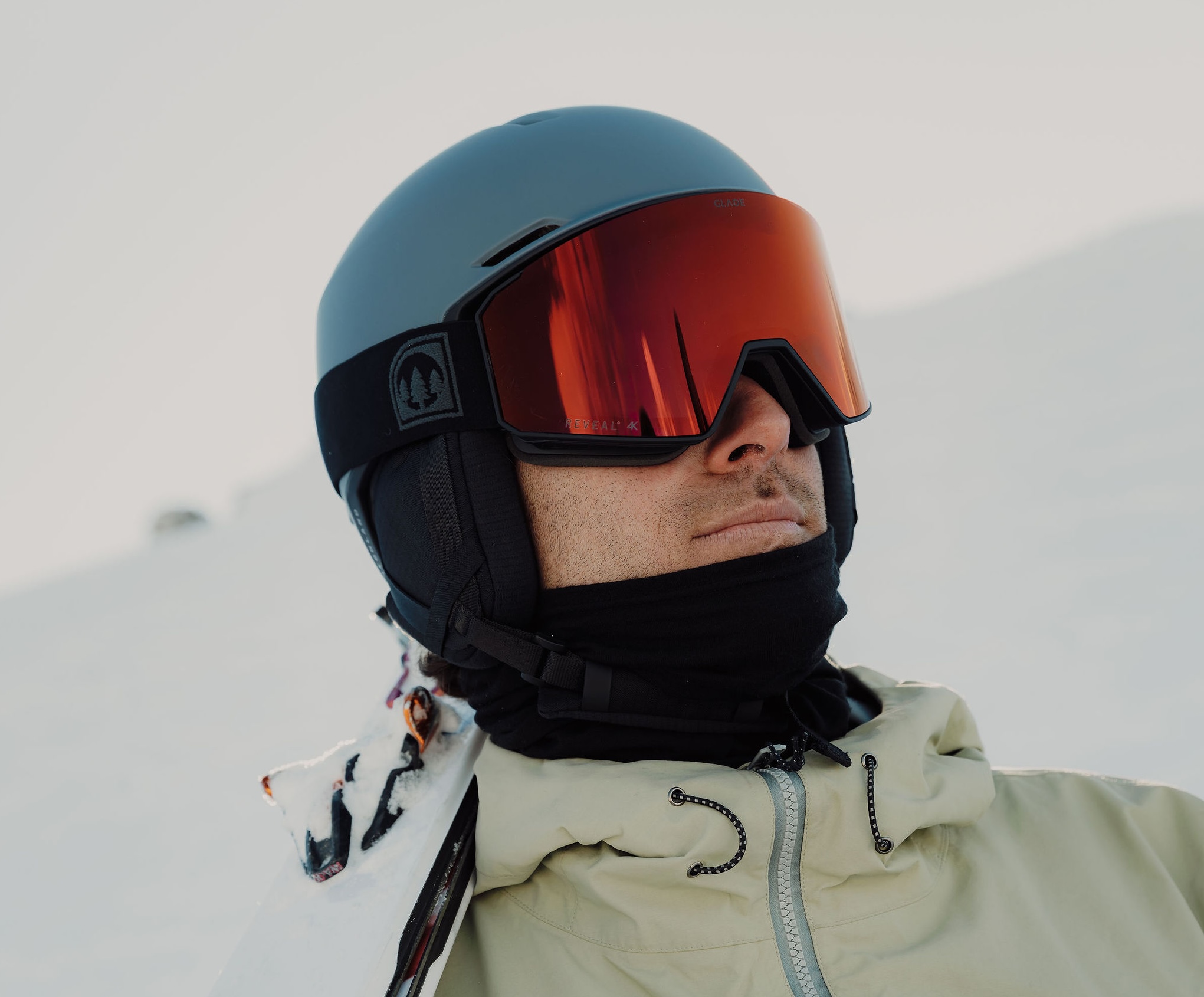 Person wearing a helmet and goggles, looking confidently at snowy surroundings.