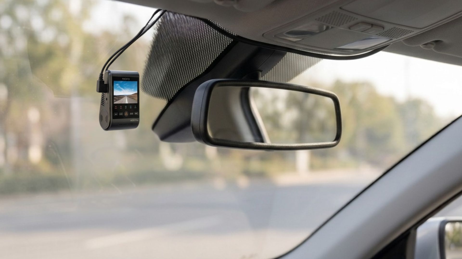 Dashboard camera mounted near rearview mirror inside a car.