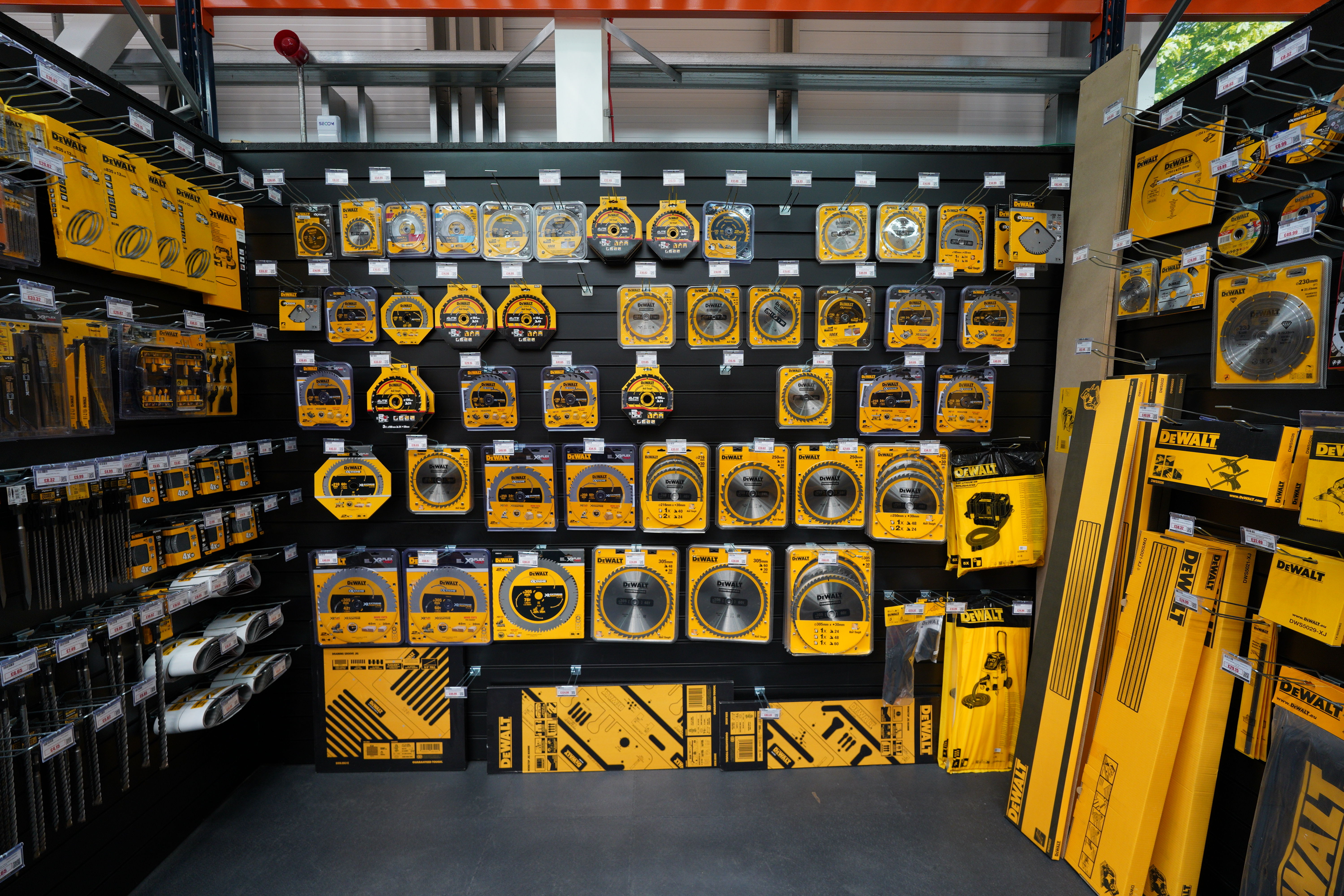 Display of various yellow tools and accessories on a black wall.