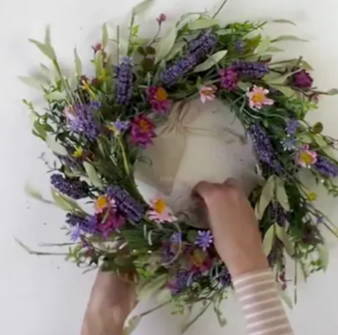Person wrapping the micro lights around her wreath with even spacing.
