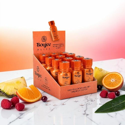 Display of orange beverage bottles with fruit on a marble surface.